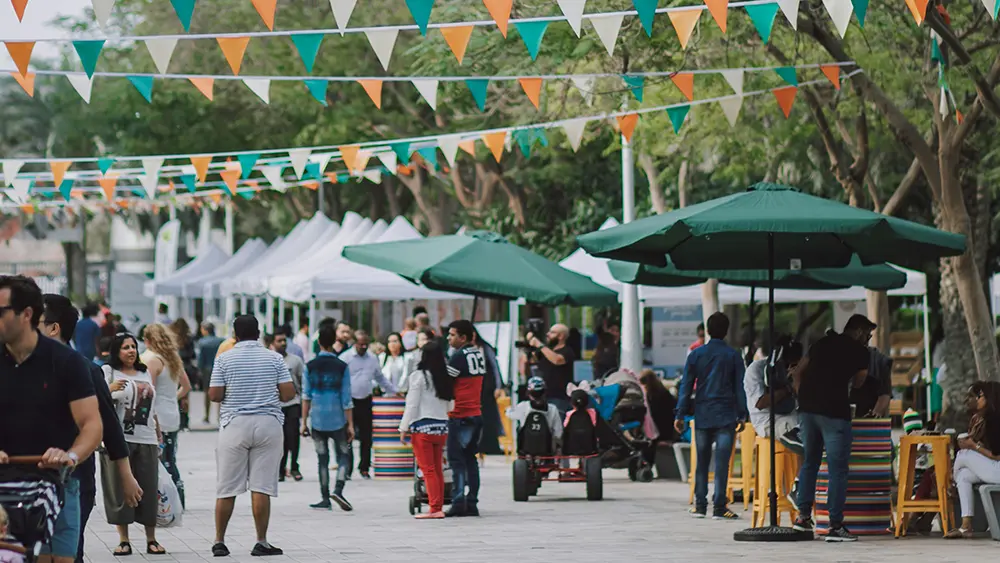 Gente caminando y socializando en un evento al aire libre. 