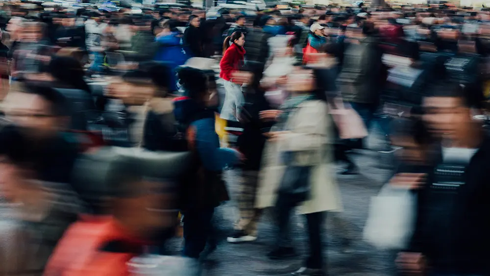 Multitud de personas moviéndose rápidamente en un espacio público.